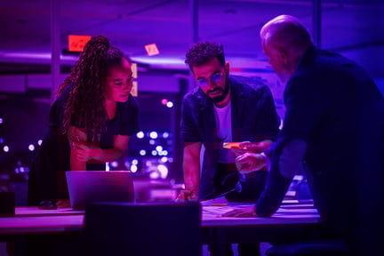 group of three people discussing a project around a table