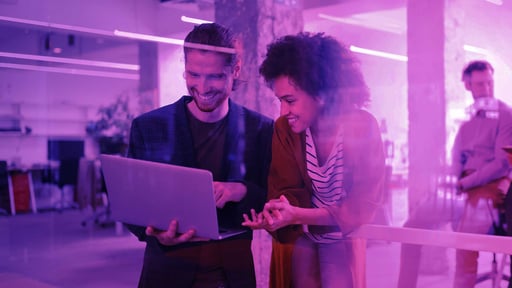 man and woman smiling and looking at laptop