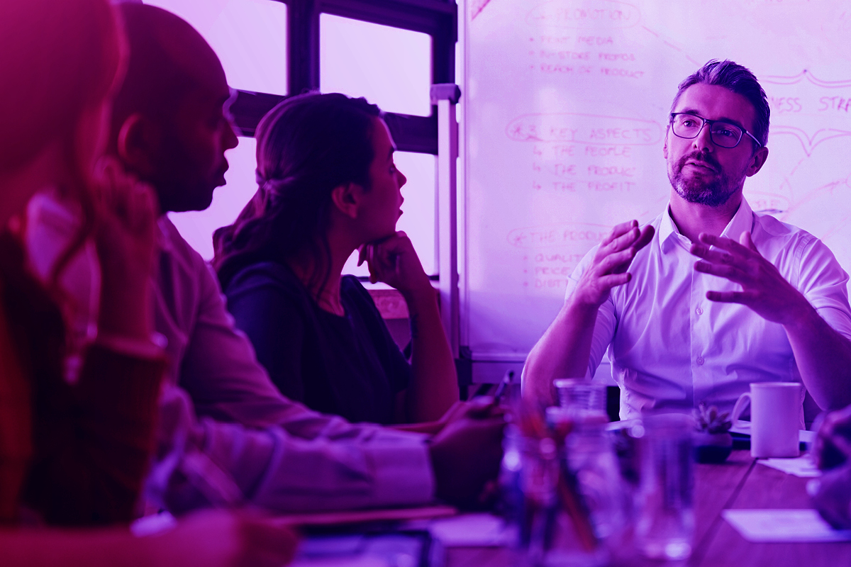 Man talking to a group of people around a table
